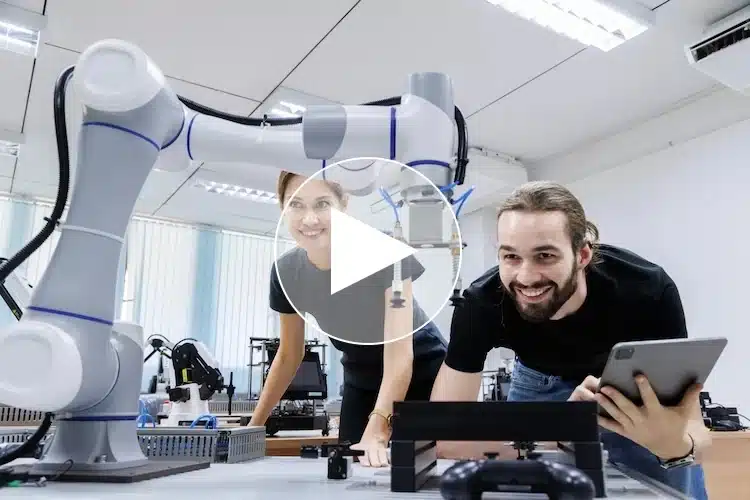 Zwei junge Auszubildende in einem modernen Ausbildungszentrum der Kunststoffindustrie arbeiten gemeinsam mit einem kollaborativen Industrieroboter an einem technischen Projekt – Fokus auf Digitalisierung, Robotik und praxisnahe Ausbildung in zukunftsorientierten Berufen.
