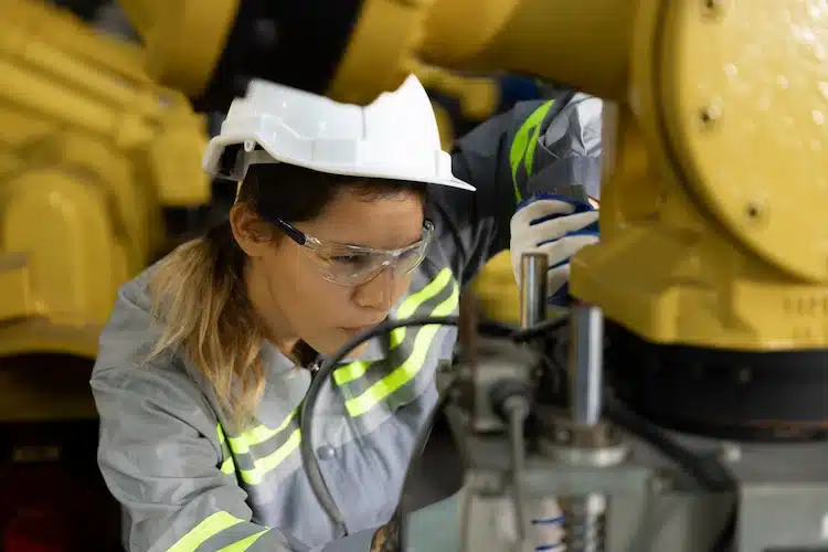 Junge Auszubildende zur Maschinen- und Anlagenführerin in der Kunststoffindustrie arbeitet konzentriert an einer industriellen Fertigungsanlage – praxisnahe Ausbildung im technischen Bereich.
